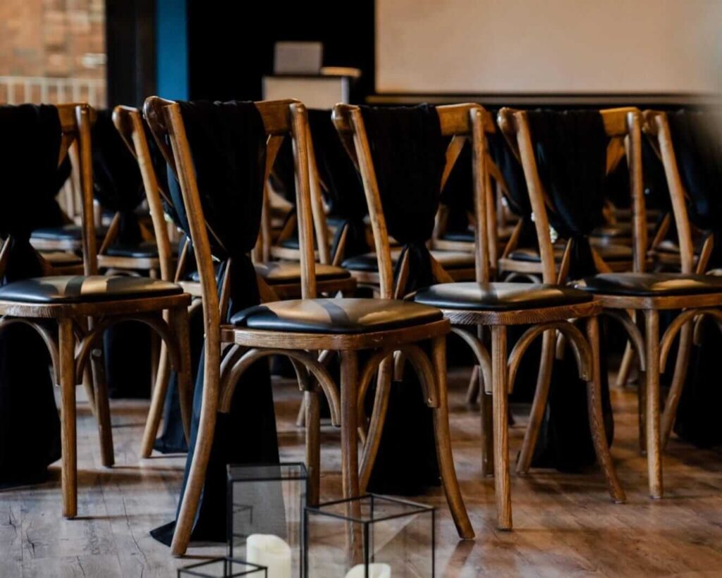 Dress my venue with wooden chairs, black drapes and lanterns for a modern ceremony look.