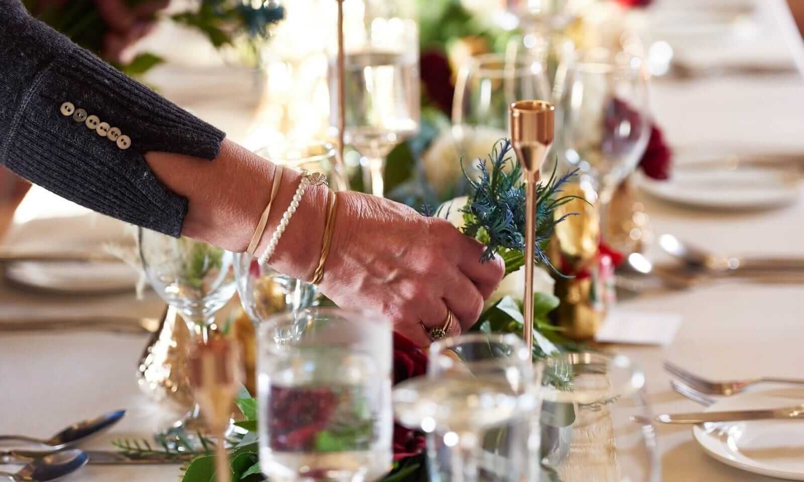 Event planners arranging flowers on an elegant wedding table runner.