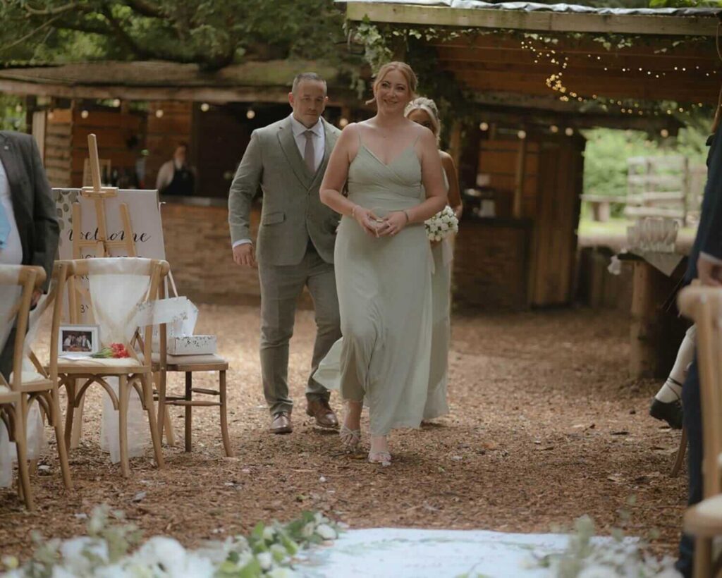 Bridesmaid walking up the aisle at a forest wedding ceremony.
