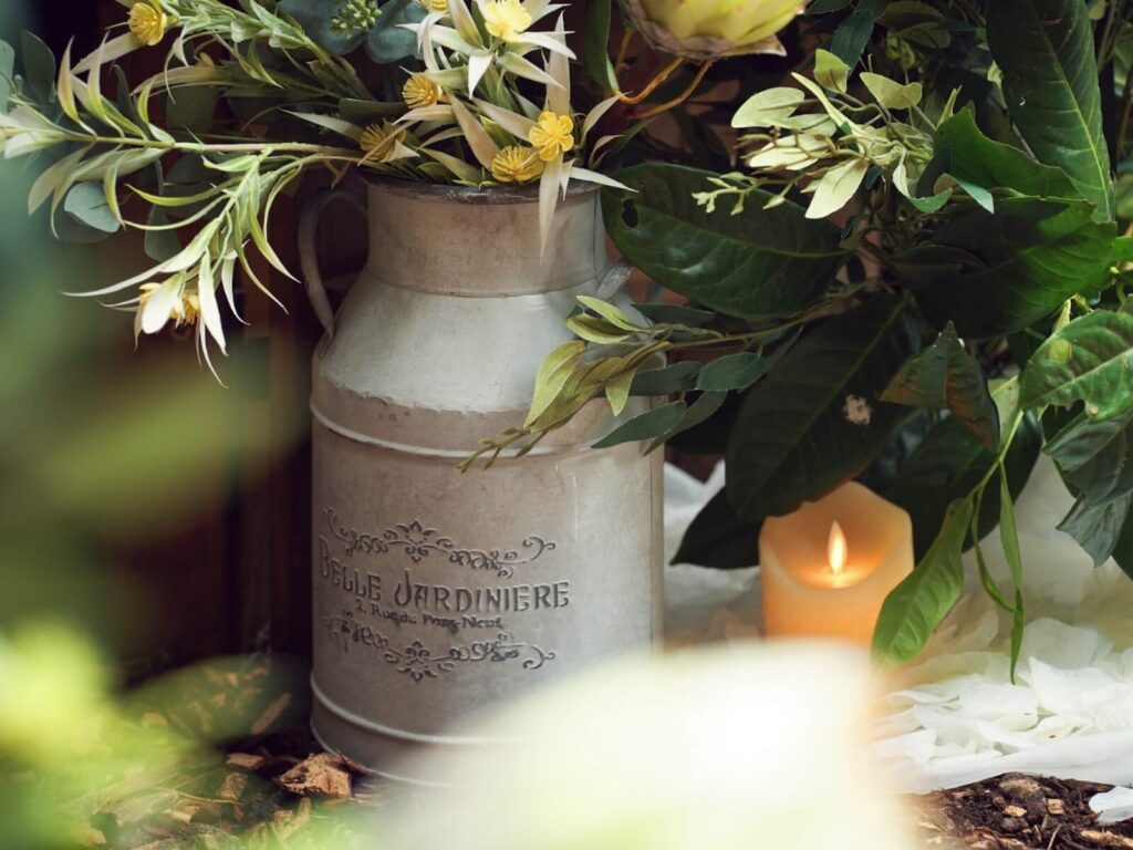 The Secret Forest entrance decor with rustic milk churn flowers and a candle.