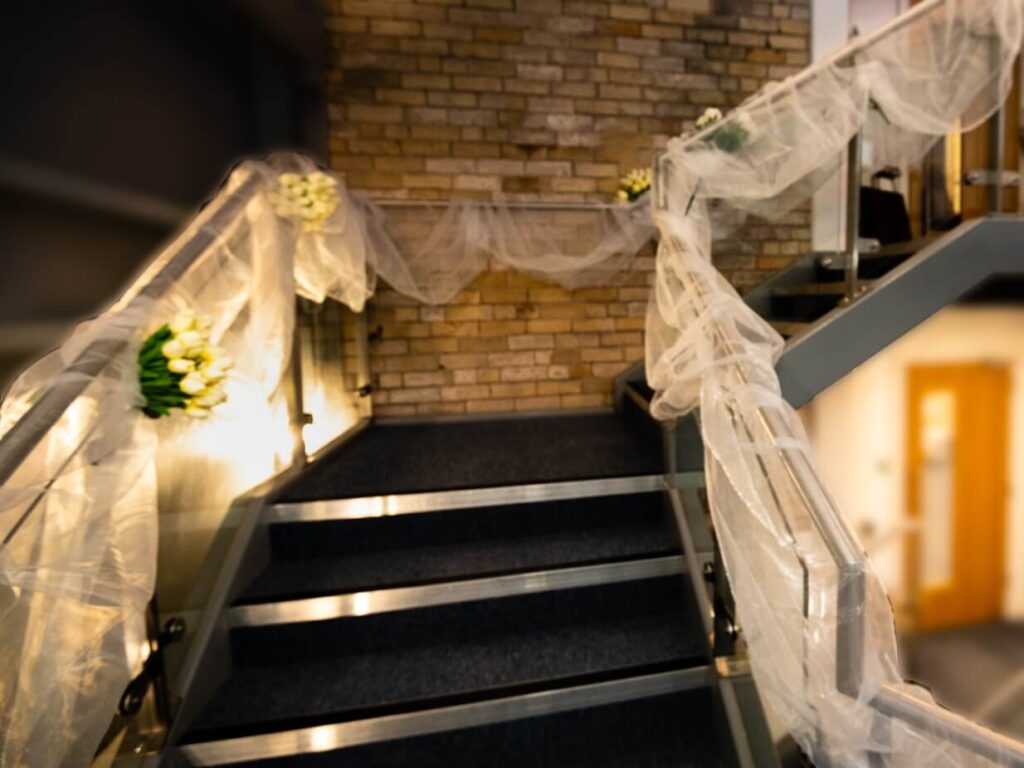 Warm lighting on a decorated staircase with soft tulle and white flowers.