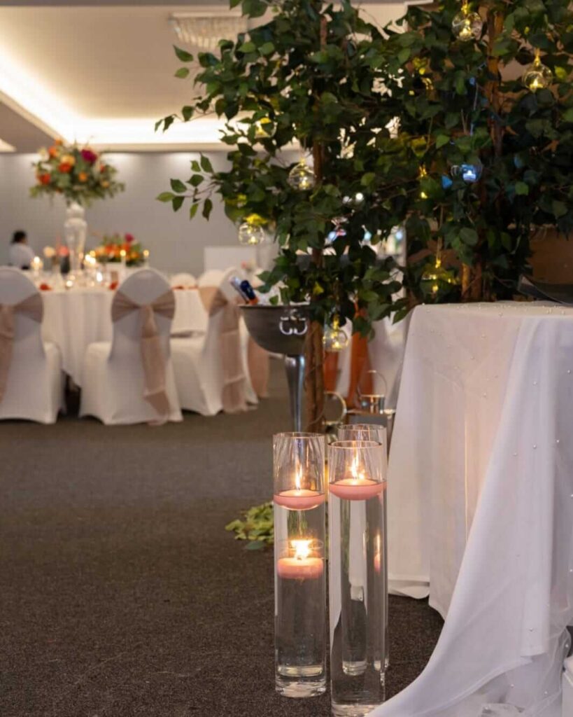 Rustic party lights with floating candles and greenery leading into an elegant wedding reception.