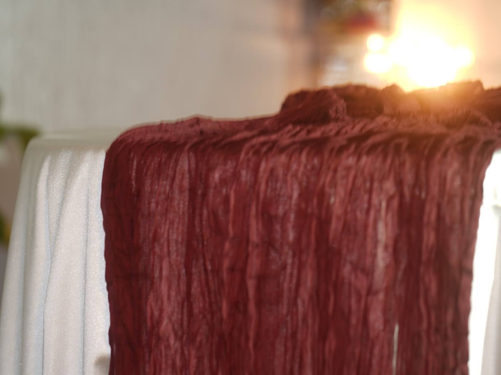Burgundy cheesecloth table runner styled for wedding decor hire in Doncaster on a dressed reception table.