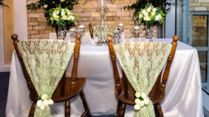 Chair decorations with lace drapes and floral ties for a styled top table