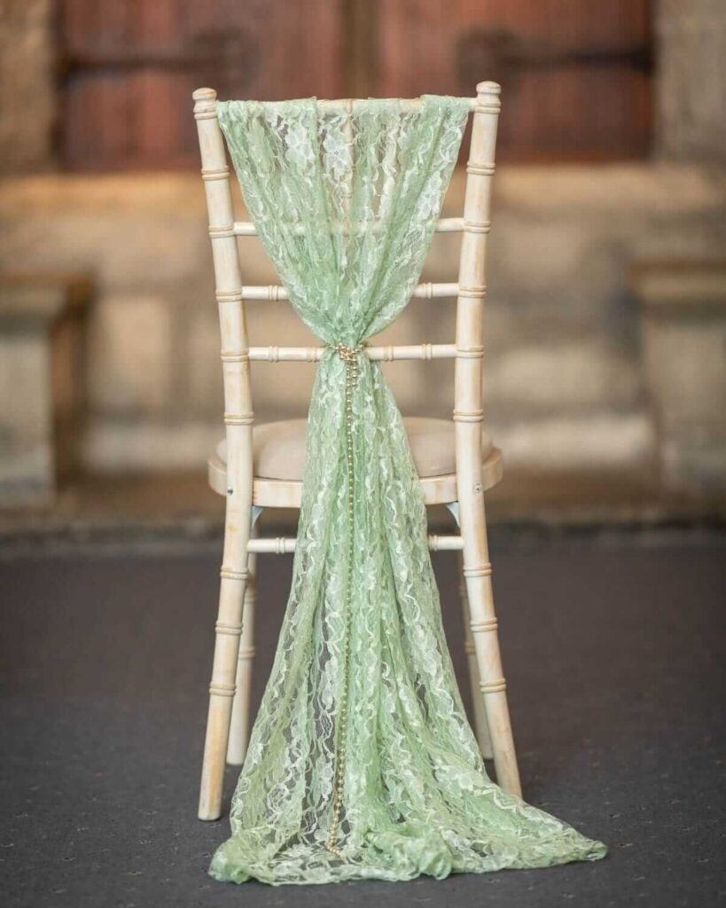 Sage green lace chair drape with gold chain detail on chiavari chair