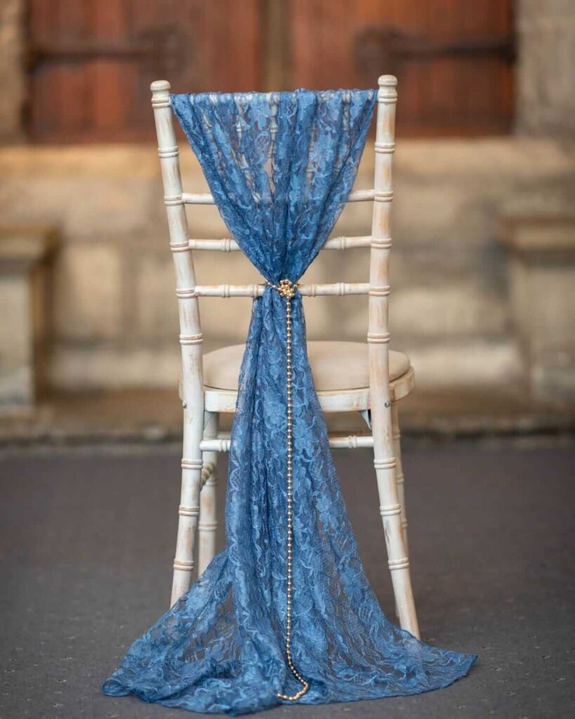 Chair décor (chair decor) with blue lace drape and gold chain on a chiavari chair