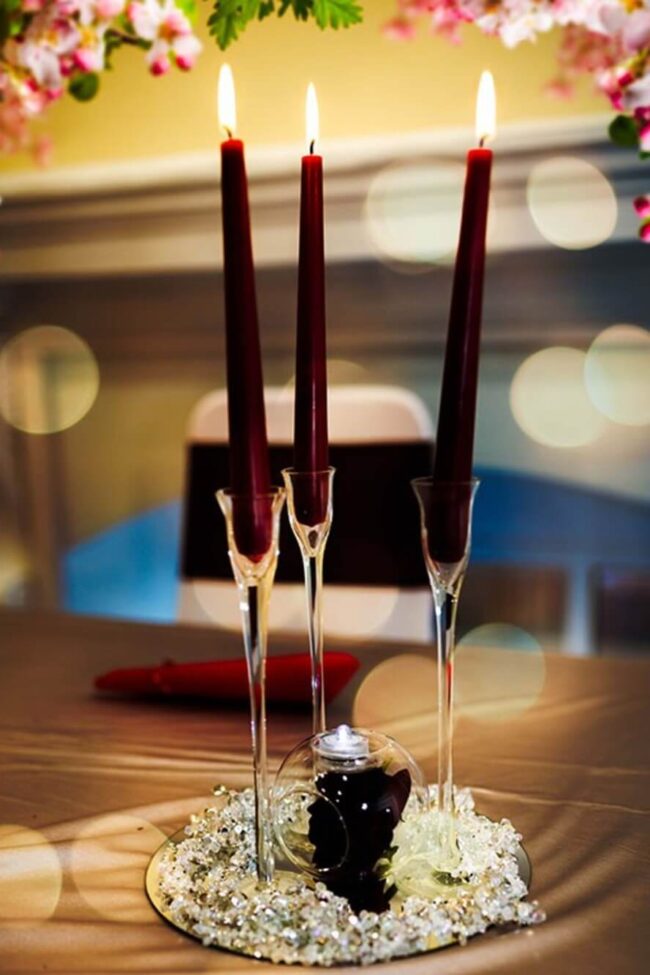 Clear taper candle holders trio with deep red taper candles on a mirrored base