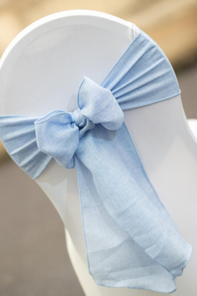 Baby blue sashes tied in a bow on a white venue chair