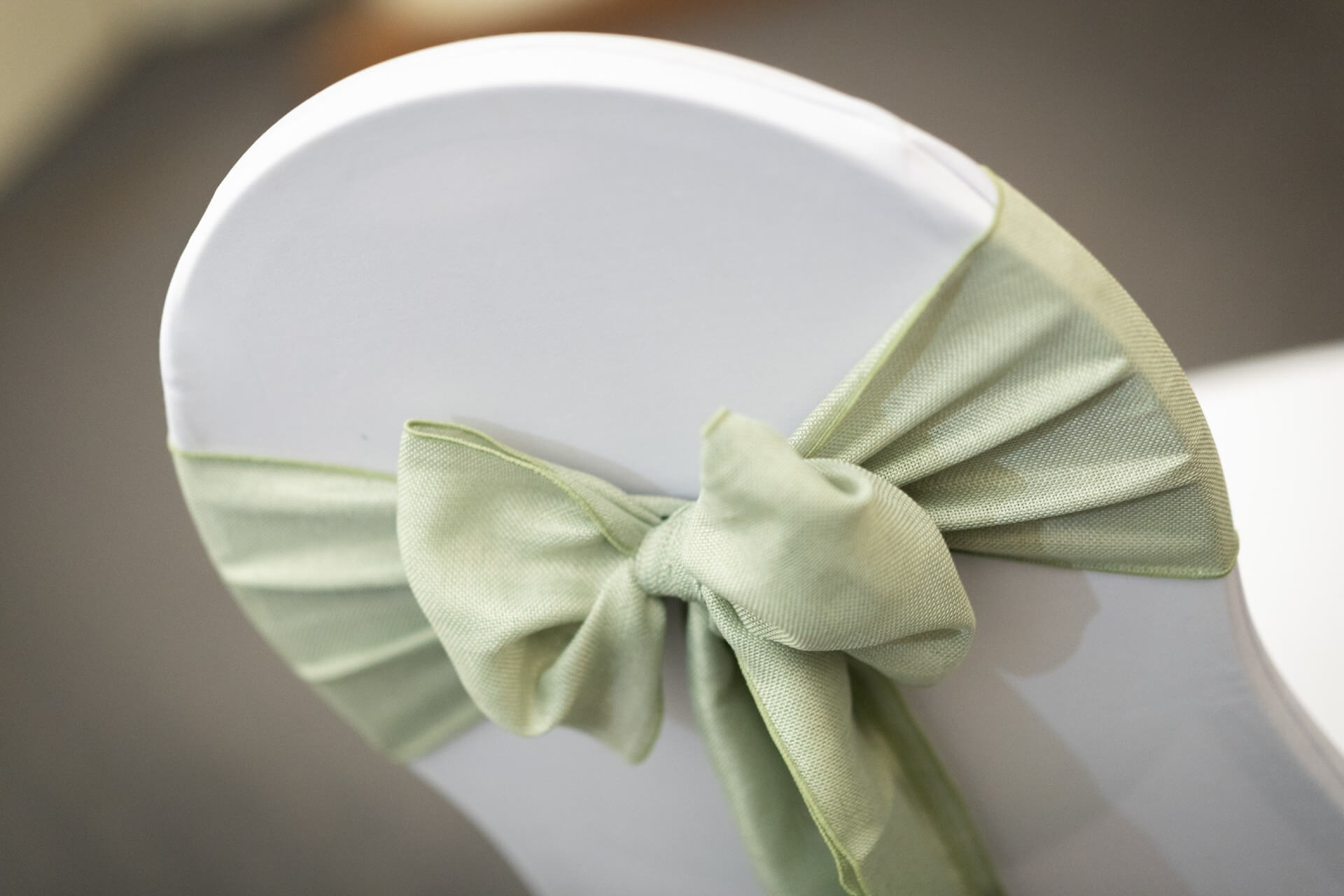 Close-up of sage burlap sash bow detail on a chair cover
