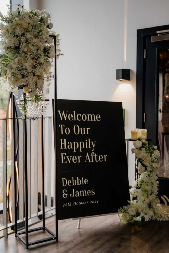 Welcome sign board styled with white florals and LED candles for a venue entrance
