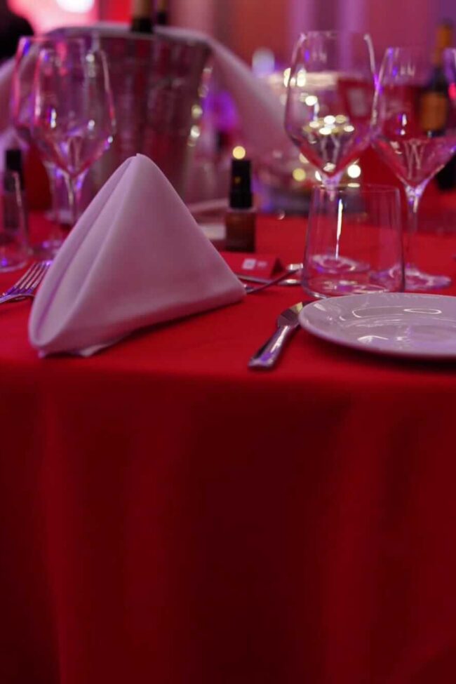 Red cloth tablecloths on a round banquet table with place settings and glassware