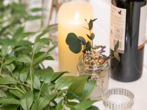 pillar candle with greenery and bud vase on table