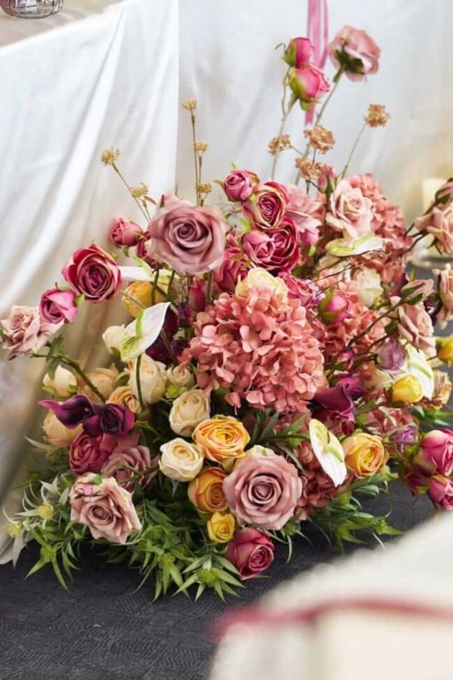 Wedding aisle flowers styled as a bespoke floor arrangement for ceremony décor