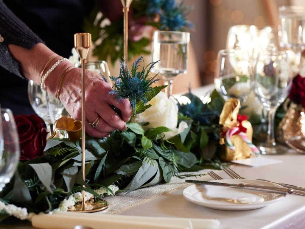 Artificial flower garland styled across a table with flowers and greenery