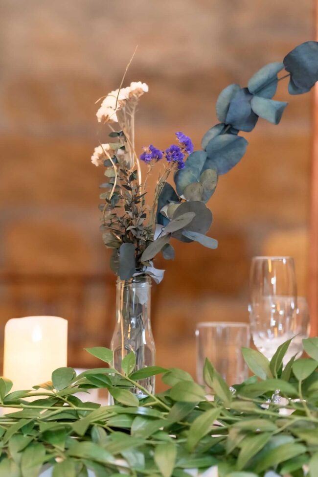 Dried floral arrangements displayed in a small glass vase on a styled table