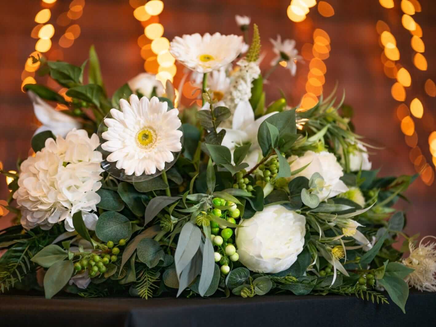 Top table wedding flowers styled as a bespoke artificial floral arrangement