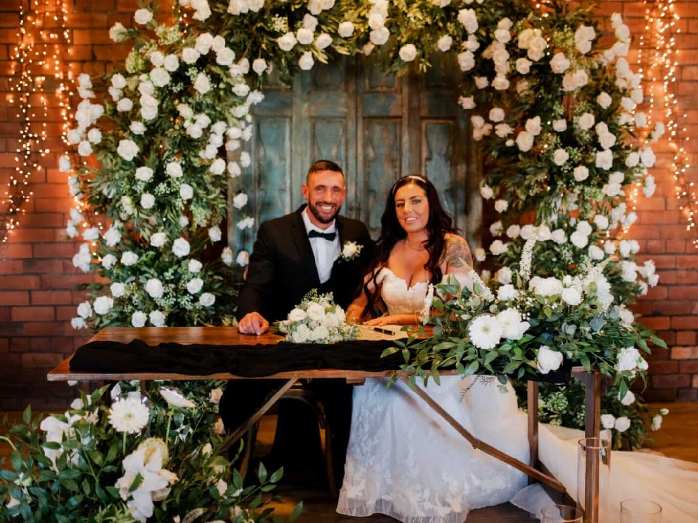Artificial top table flower arrangement styled across the front of a wedding table