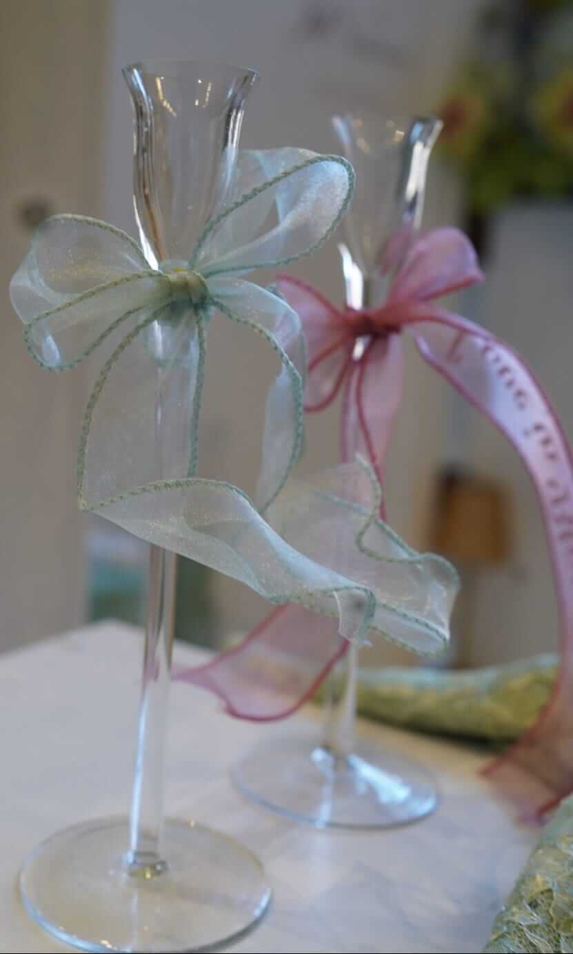 Table place names styled on soft ribbon bows around wedding glassware