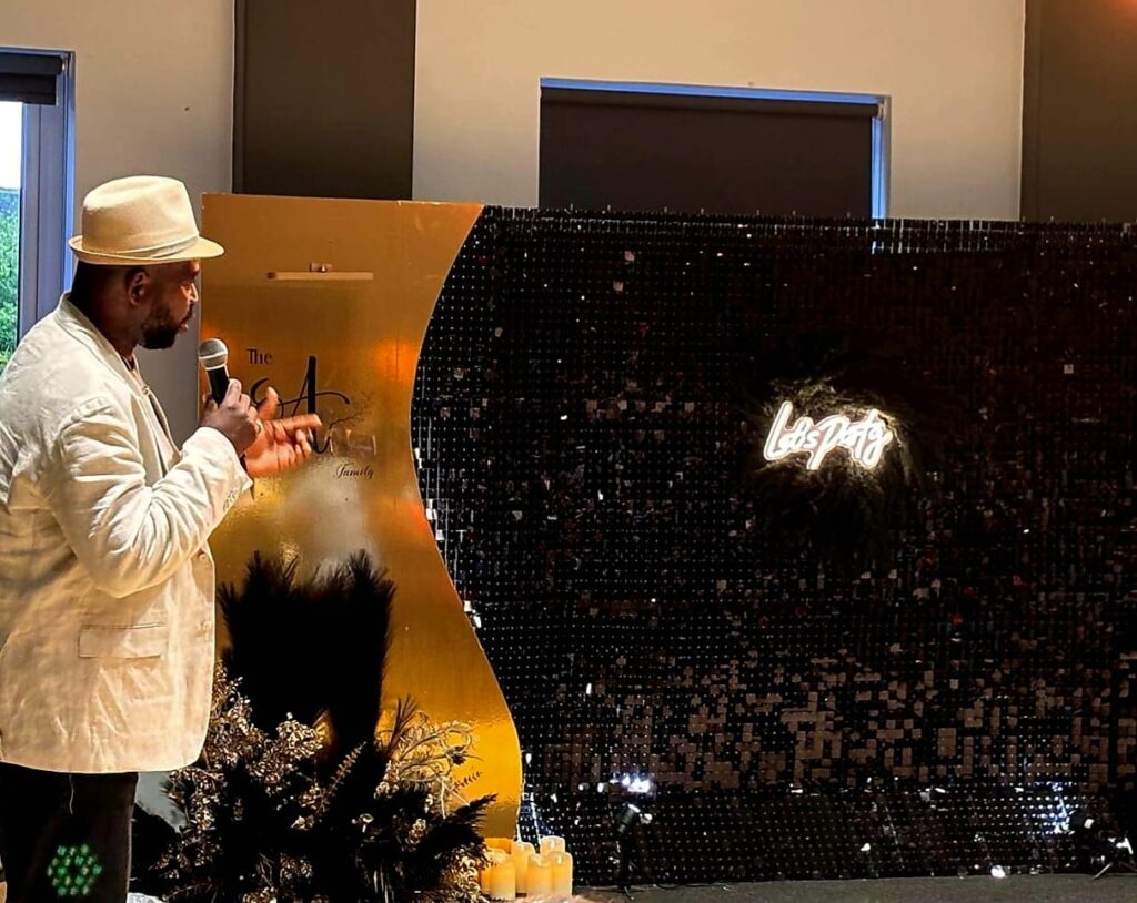 Black shimmer wall with illuminated party sign at an indoor celebration