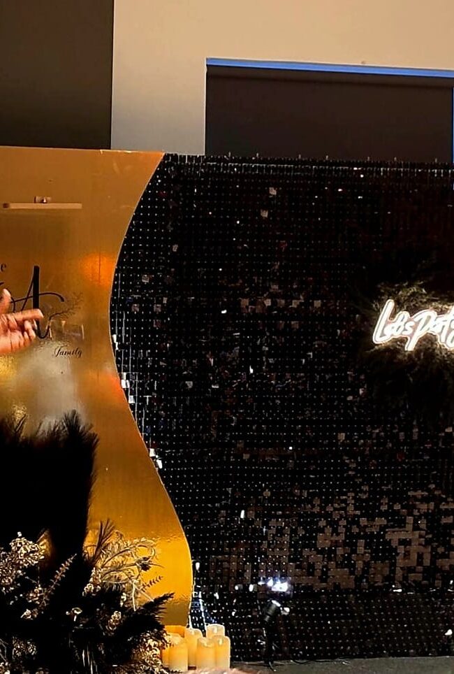 Black shimmer wall with illuminated party sign at an indoor celebration