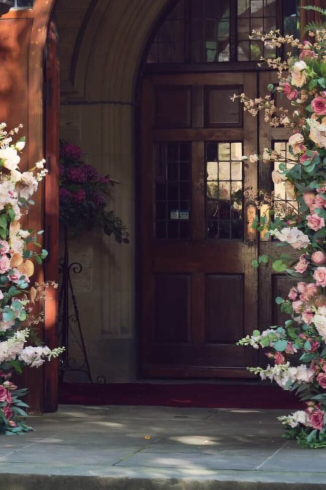 Broken floral arch hire with two pink and white flower pillars framing a wedding venue entrance