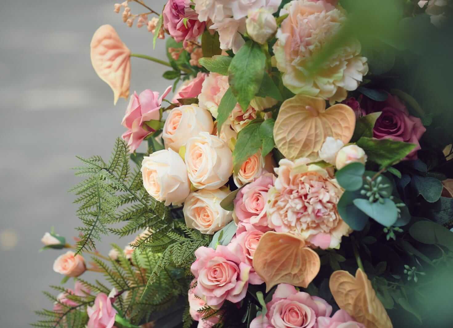 Close-up of pink and cream broken arch wedding flowers with green foliage