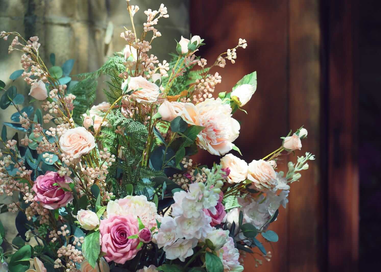 Upper detail of wedding floral pillars with pink and cream roses and greenery