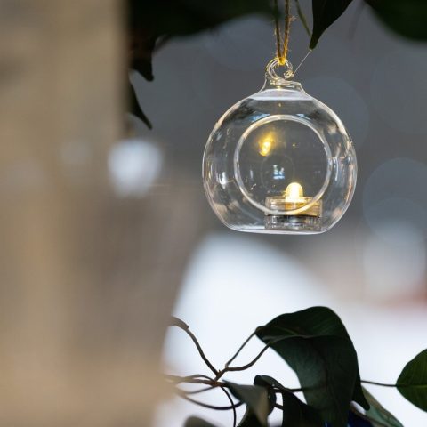 Glass hanging bauble with candlelight, styled for elegant wedding hire decor.